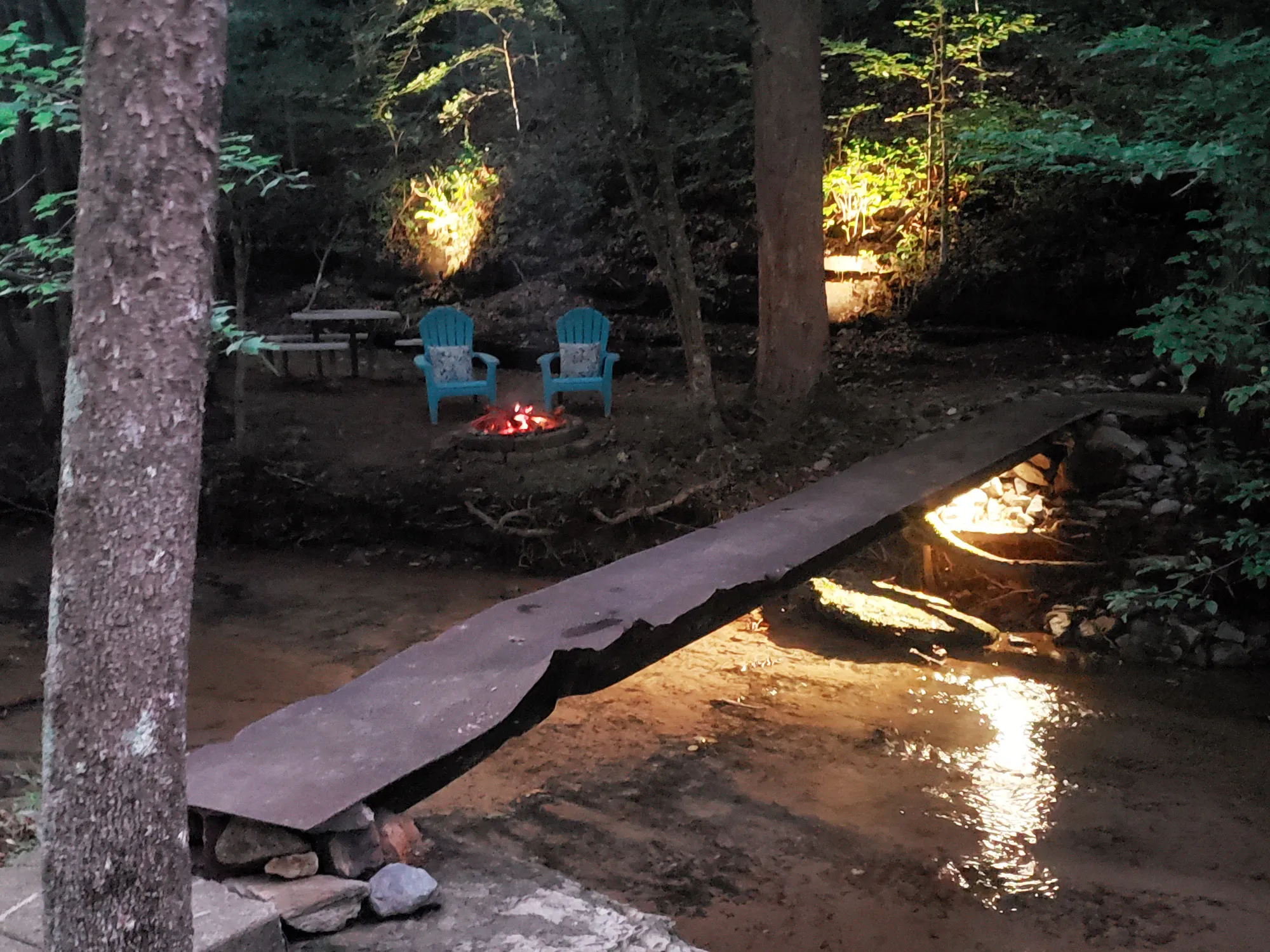 Fire pit and seating area beside the creek at dusk