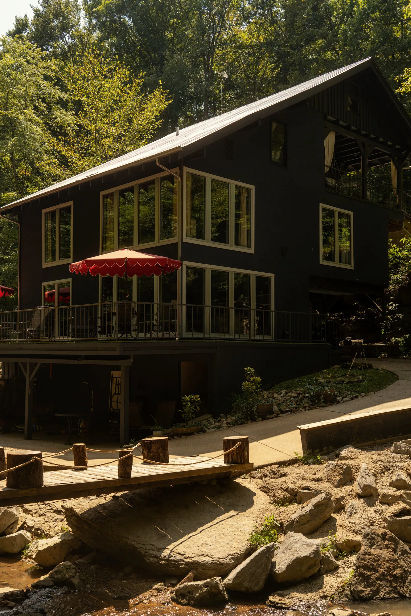 The Waterfall House seen from the creek bed, its red umbrella open above the rocks