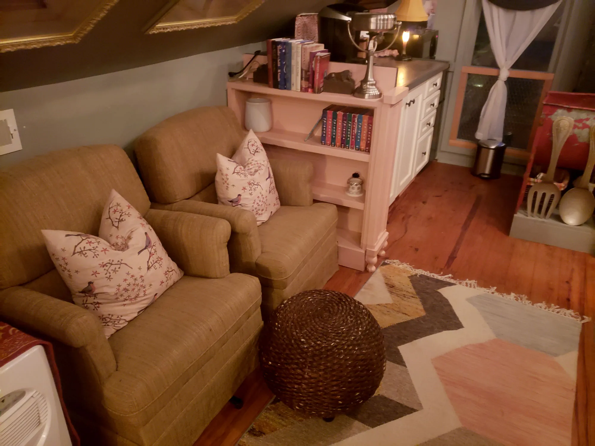An interior sitting room with a linen sofa, bookshelves, and folk art on the walls