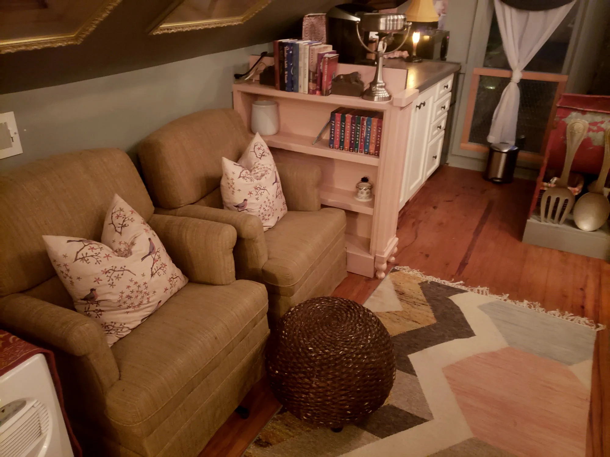 An interior sitting room with a linen sofa, bookshelves, and folk art on the walls